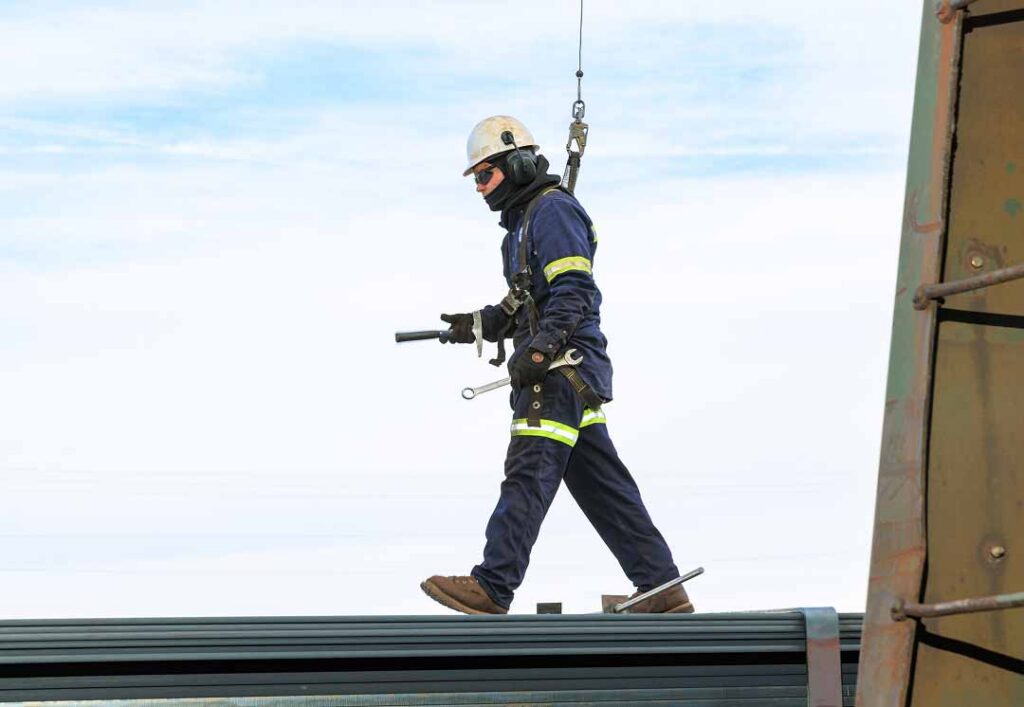 Worker walking across beam attached to safety line
