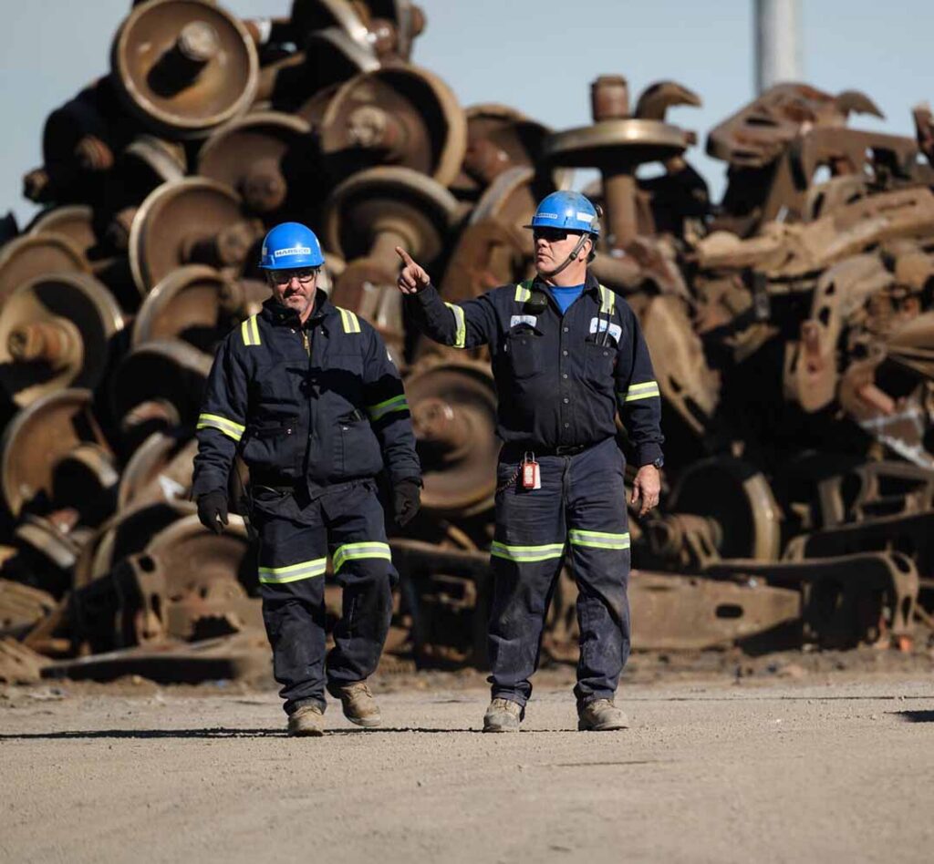 Workers on site with pile of steel pieces behind them