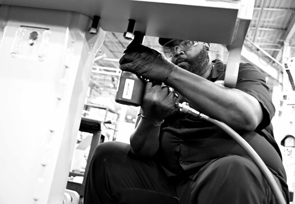 Worker installing screws on factory machine
