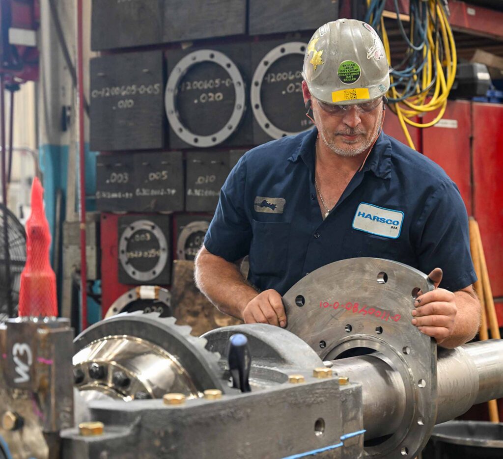 Worker in workshop working with metal pieces on machine